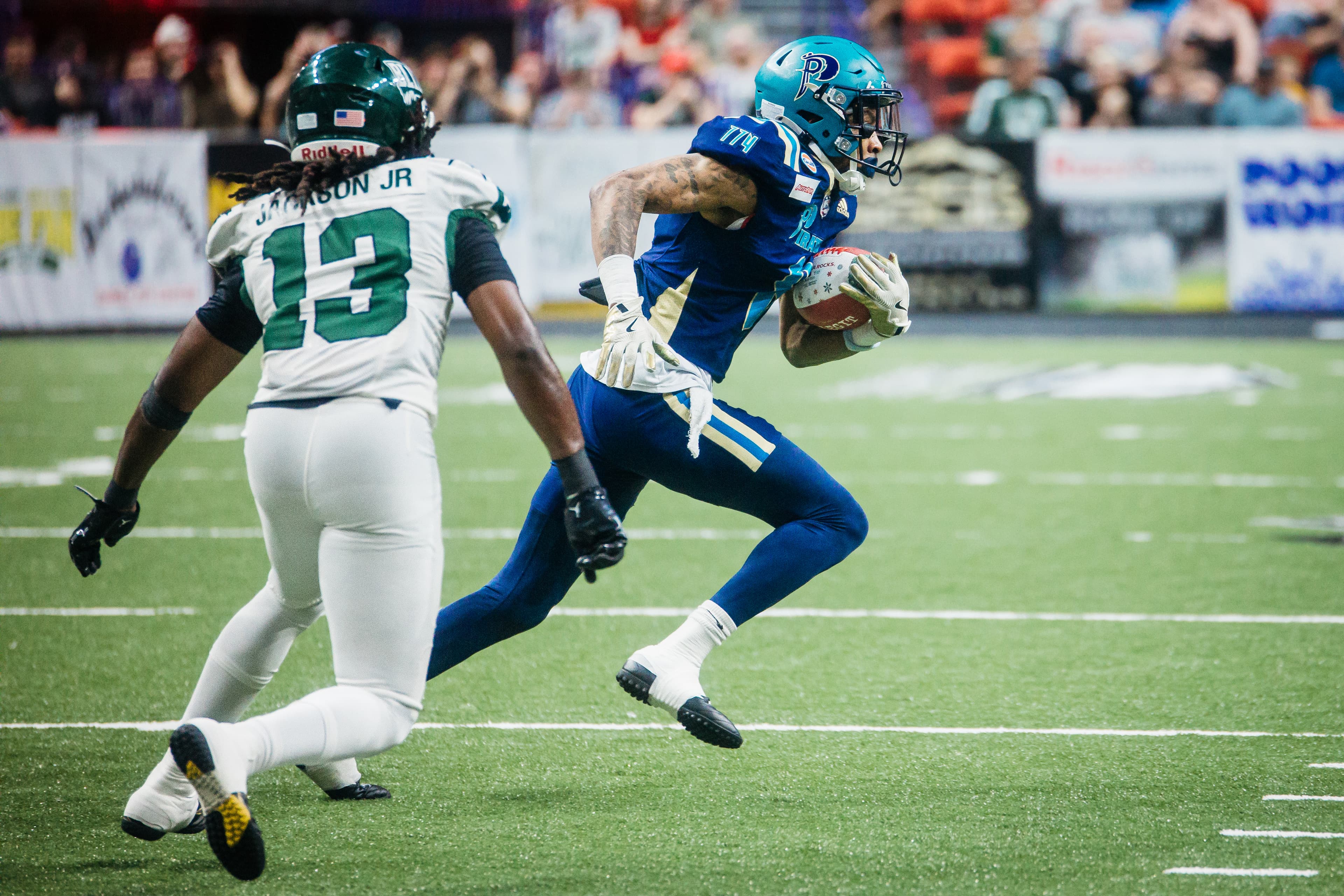 Peak action at the IFL — receiver leaping for a catch above the turf at arena level.